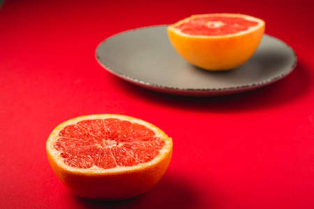 Sliced grapefruit on vibrant red backgroundの写真素材