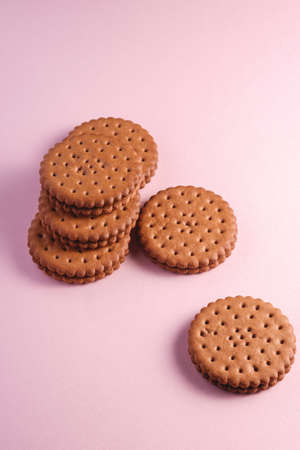 Chocolate sandwich cookie with cream on pink backgroundの写真素材