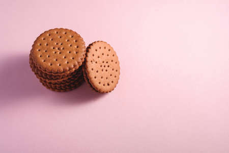 Chocolate sandwich cookie with cream on pink backgroundの写真素材