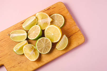 Fresh tasty lemon and lime citrus fruits slices on pink backgroundの写真素材