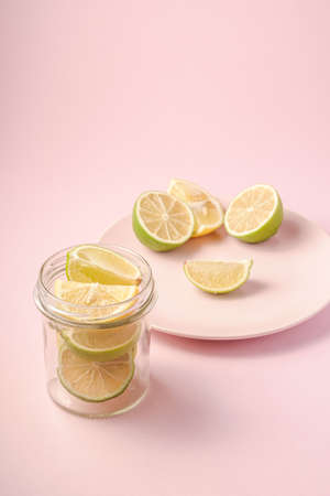Fresh tasty lemon and lime citrus fruits slices on pink backgroundの写真素材