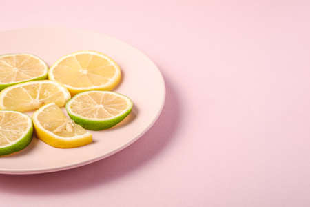 Fresh tasty lemon and lime citrus fruits slices on pink backgroundの写真素材
