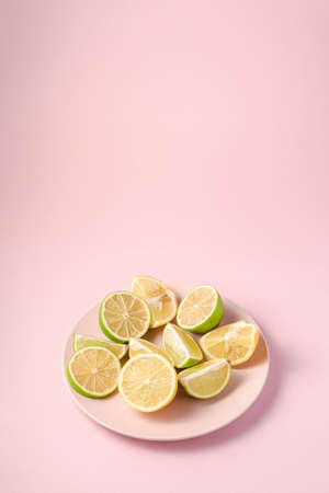 Fresh tasty lemon and lime citrus fruits slices on pink backgroundの写真素材