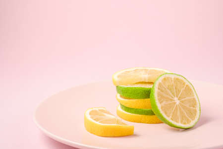 Fresh tasty lemon and lime citrus fruits slices on pink backgroundの写真素材