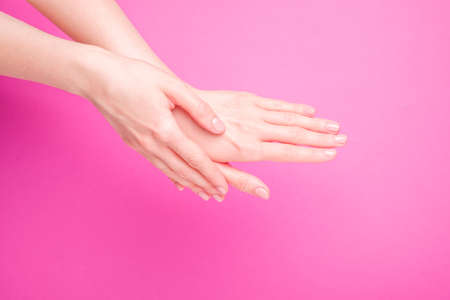 Beautiful female hands showing fresh cute manicure, skin and nail care concept, pink background