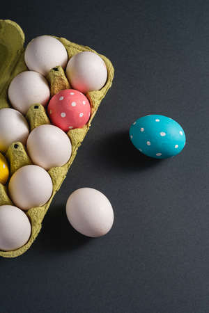 Colorful polka dot Easter eggs in egg tray on dark background, greeting card