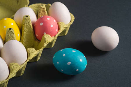 Colorful polka dot Easter eggs in egg tray on dark background, greeting card