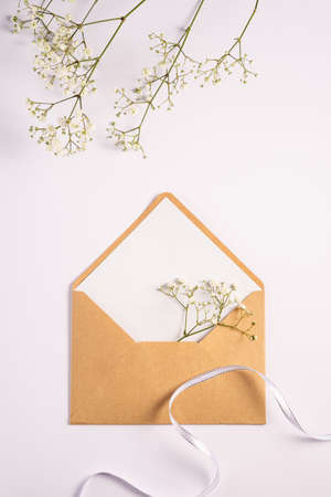 Kraft brown paper envelope with white empty card, gypsophila flowers, white background, mockup blank letterの写真素材