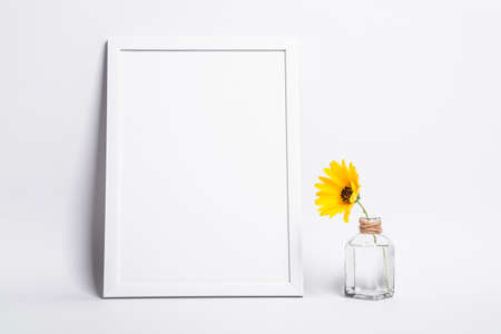 White empty picture frame mock up with yellow flower in glass jar
