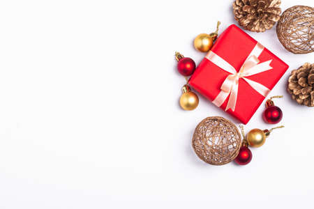 Christmas composition. Red gift box, pine cones, gold and red ornament decorations on white background. Winter holidays concept. Top view copy spaceの写真素材