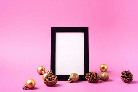 Christmas minimal composition with empty picture frame. Golden ornament, pine cones decorations....