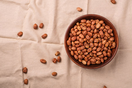 Hazelnuts in wooden bowl on linen cloth background, natural healthy vegan food, top view