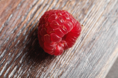Raspberry fruit on old wooden cutting board, healthy summer berry, angle view macroの写真素材