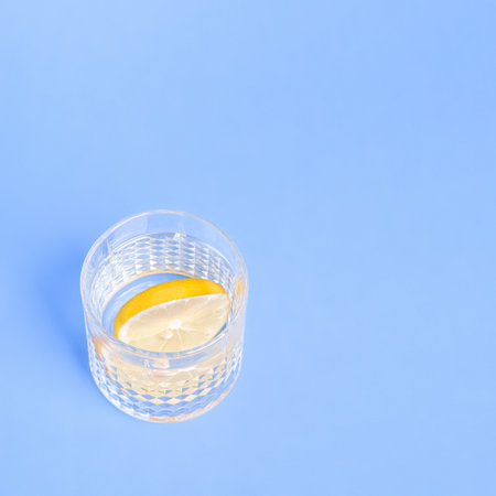 Glass with water and lemon on blue background