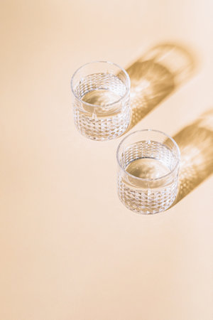Glass of water on pastel background with hard shadowの写真素材