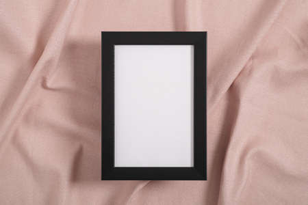 Black picture frame with white mockup on a pink textile