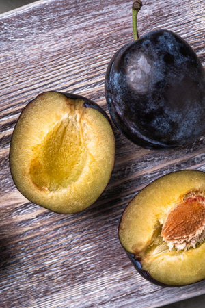 Fresh ripe plum fruits whole and sliced on wooden cutting boardの写真素材