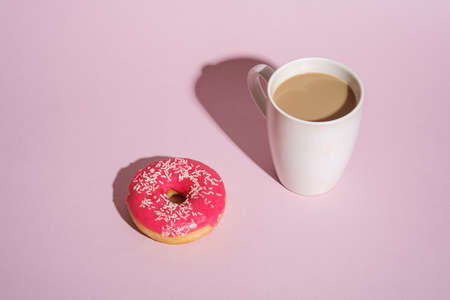 Pink donut with sprinkles near to cup of coffeeの写真素材