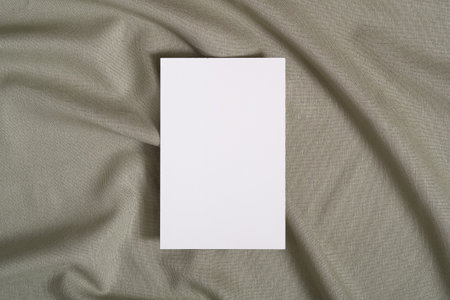 White blank paper card mockup on green neutral colored textile