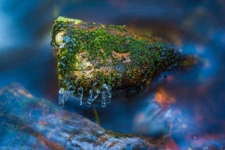 Long exposure shot of flowing water and mossy rockの写真素材