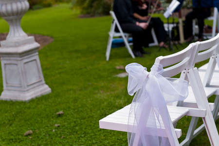 Chairs with white ribbons in an outdoor garden weddingのeditorial素材