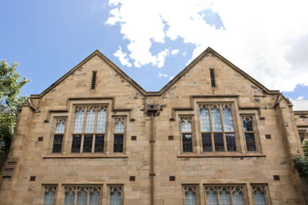 Upward view of a gothic styled building with the window showing the reflection of the skyの写真素材