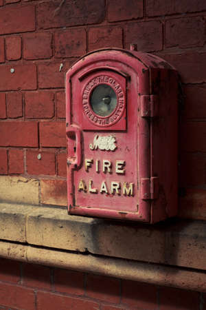 An old fire alarm hanging on the brick wallの写真素材