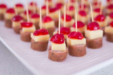 Appetizers with cherry, cheese and salami skewed on a toothpick placed in a tray