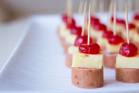 Appetizers with cherry, cheese and salami skewed on a toothpick placed in a trayの写真素材
