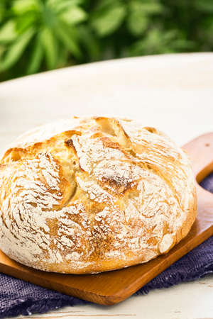 Round Loaf of Sourdough Bread on a Cutting Board on a Table Outside