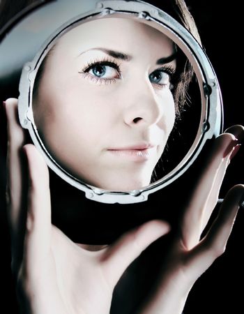 Bewitching portrait of beautiful girl looking through spherical metal capacity.の写真素材
