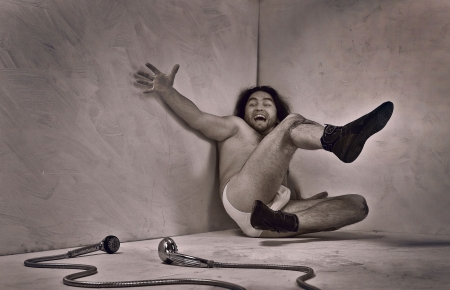 Undressed man in underwear and boots sit in grey room. 
の写真素材