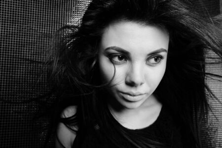 Beautiful young brunette in black dress on black backgroundの写真素材