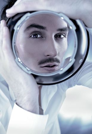 Bewitching portrait of beautiful man looking through spherical metal capacityの写真素材