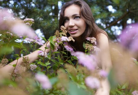 beautiful girl sitting among the bush flowers. Photo.