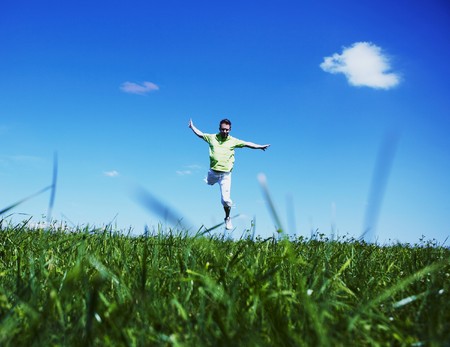 Jumping up guy in a green shirt against blue sky.の写真素材