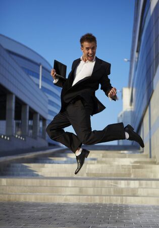 Jumping businessman over urban backgroundの写真素材