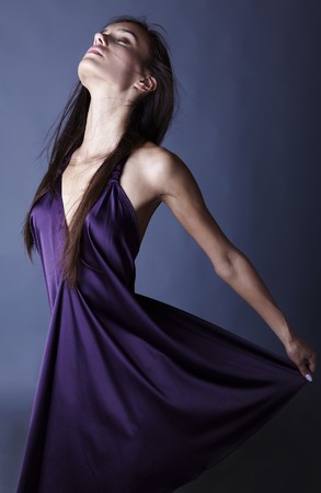 Sexy brunette posing in silk violet dress.の写真素材