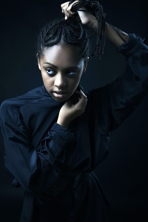 Portrait of a beautiful young black woman posing in black background.の写真素材