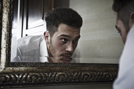 Man takes a look at himself in the mirror.の写真素材
