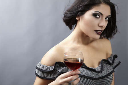 Studio portrait of a beautiful brunette holding a glass of red wine.の写真素材