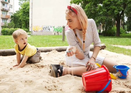 Beautiful young girl sits in a children s sandbox  の写真素材