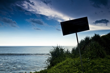 Old funny wooden caution sign on the beach  