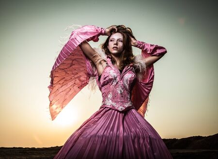 Attractive romantic woman on beautiful pink dress pose outdoor  の写真素材