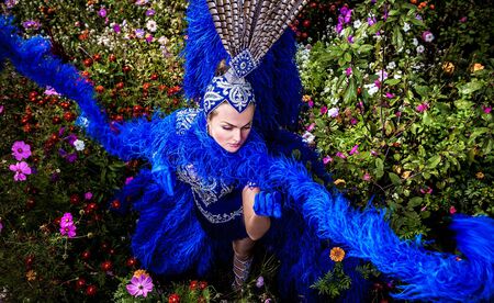 Woman in expensive exotic carnival suit pose in meadow of flowers  の写真素材