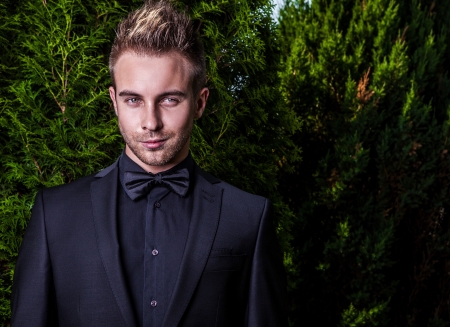 Portrait of young beautiful fashionable man against summer garden  の写真素材
