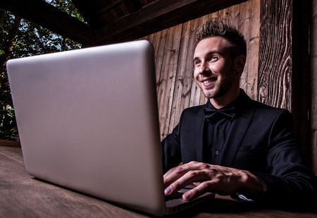 Young beautiful fashionable man with notebook against wooden wall  の写真素材