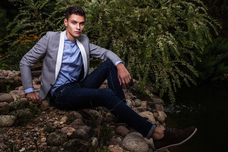 Portrait of young beautiful fashionable man against autumn garden  