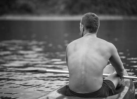 Black-white photo of man who siting back on river kayakの写真素材