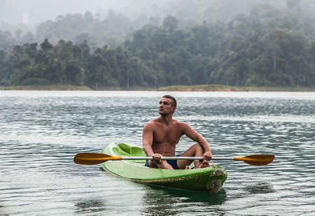 Strong young man in kayak on the picturesque lake in Thailand の写真素材